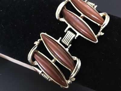 Sale Photo Thumbnail #96: Mid-century vintage gold tone link bracelet set with brown/caramel lucite or resin navette cabochons. Features sculpted scroll-like metalwork and a fold-over clasp. Measures approximately 7 inches in length. In good vintage condition with minor surface we