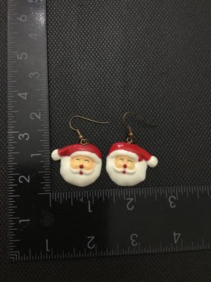 Sale Photo Thumbnail #236: A pair of festive Christmas Santa Claus face dangle earrings. Made of painted resin or plastic with brass-tone French wire ear hooks. The Santa face charms measure approximately 1 inch in width and height. Pre-owned in good condition with minor surface we