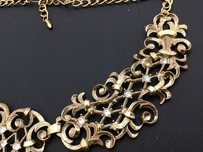 Sale Photo Thumbnail #5: A vintage Jose Barrera for Avon gold-tone collar statement necklace featuring intricate filigree scrollwork set with clear rhinestones. Includes an adjustable hook closure with an extender chain. Hallmarked 'Barrera for Avon' on the back. The necklace mea