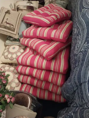 Sale Photo Thumbnail #66: Stack of pink and beige striped tufted outdoor chair cushions displayed alongside decorative throw pillows.