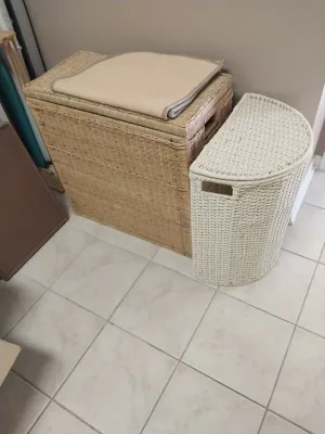 Sale Photo Thumbnail #99: Two woven wicker laundry hampers, including a large natural tan rectangular unit with a flat lid and a smaller white semi-circular basket.