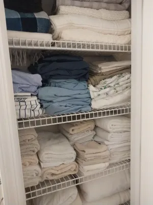 Sale Photo Thumbnail #72: Linen closet packed with neatly folded towels, bed sheets, and blankets arranged on white wire shelving.