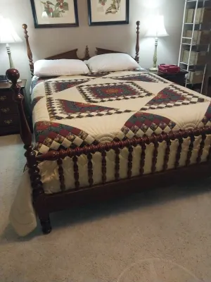Sale Photo Thumbnail #76: Traditional wooden four-poster bed frame with a spindle footboard, topped with a geometric patch-work quilt and matching pillows.