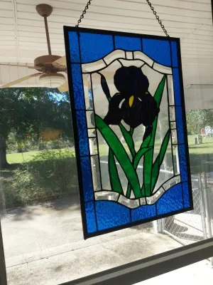 Sale Photo Thumbnail #103: Rectangular stained glass window suncatcher featuring a dark purple or black iris with green leaves framed in blue and bevel-cut clear glass.