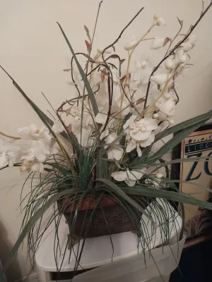 Sale Photo Thumbnail #63: Large artificial white orchid floral arrangement set in an ornate dark metal planed pot.