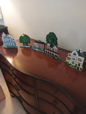Sale Photo Thumbnail #22: Collection of Cat's Meow Village wooden decorative house collectibles displayed on a traditional dark wood serpentine-front dresser.