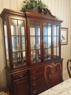 Sale Photo Thumbnail #34: Traditional dark wood china hutch featuring glass-front display cabinets with broken pediment crown molding and lower storage drawers.