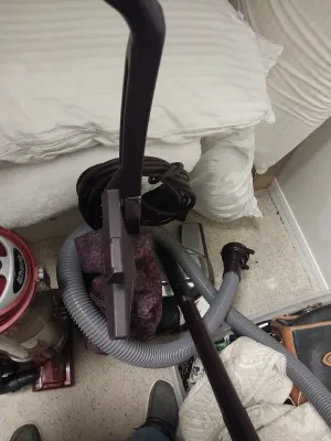 Sale Photo Thumbnail #90: Vintage Panasonic upright vacuum cleaner with attached hose and cord wrapper, stored next to a red Shark upright vacuum.