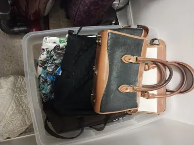 Sale Photo Thumbnail #89: Clear plastic storage tub filled with assorted women's handbags and totes, including Dooney & Bourke pebbled leather satchels and Vera Bradley patterned cloth bags.