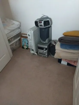 Sale Photo Thumbnail #58: Collection of household items including an Aiwa compact shelf stereo system, portable boombox, DeLonghi oil-filled radiator heater, and stacked bed linens.