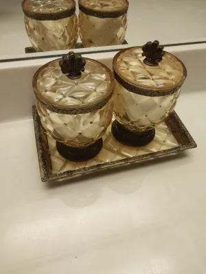 Sale Photo Thumbnail #94: Vintage amber glass vanity set including two lidded canisters with shell-motif finials resting on a matching rectangular tray.