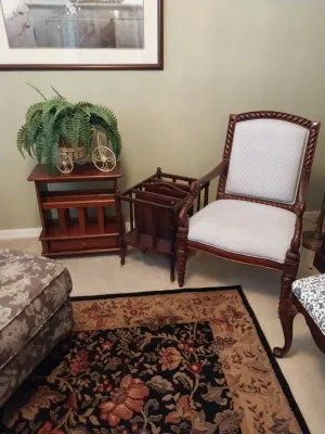 Sale Photo Thumbnail #53: Traditional wooden accent chair with light upholstery alongside a matching mahogany magazine rack and small side table.