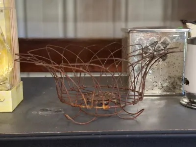 Vintage rusted wire egg or fruit basket featuring an open lattice design with flared rim and small wire feet.