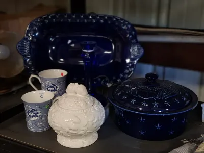 Collection of tabletop glassware and ceramics featuring cobalt blue star-motif serving pieces, a white fruit-embossed covered jar, and...