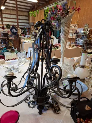 Black wrought iron scrollwork chandelier with multiple light sockets.