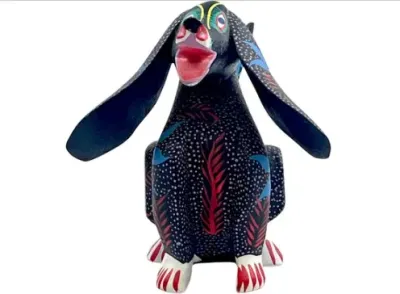 Sale Photo Thumbnail #154: Hand-painted Oaxacan wood carving alebrije dog figure featuring intricate dotted and leaf patterns with exaggerated floppy ears.