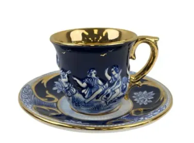 Sale Photo Thumbnail #112: Cobalt blue and gold porcelain teacup and saucer featuring raised mythological classical figure relief work and a gilded interior.