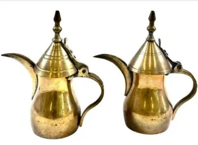 Sale Photo Thumbnail #85: Pair of vintage brass Middle Eastern or Arabic dallah coffee pots featuring decorative finials and curved handles.