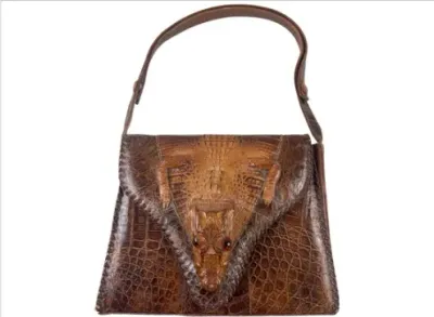 Sale Photo Thumbnail #152: Vintage brown alligator skin handbag featuring a full taxidermy baby alligator head and legs motif on the front flap.
