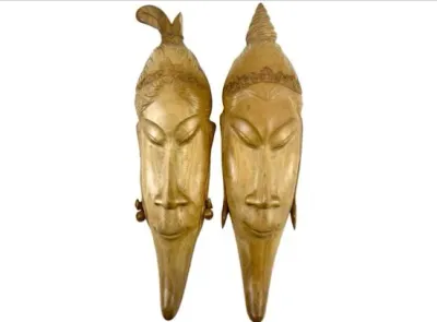 Sale Photo Thumbnail #101: Pair of vintage carved light wood Balinese masks depicting stylized faces with detailed headdresses.
