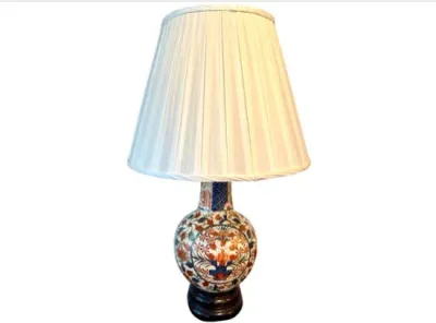 Sale Photo Thumbnail #64: Vintage Imari-style ceramic ginger jar table lamp featuring hand-painted floral motifs and a pleated cream lampshade, set on a dark wood base.