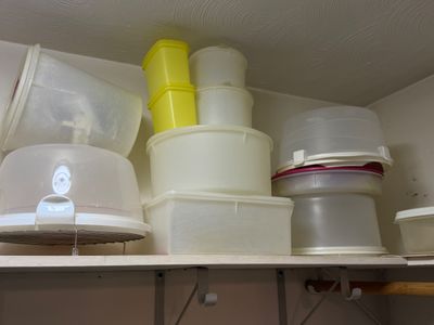 Sale Photo Thumbnail #25: Collection of vintage Tupperware and plastic food storage containers, including cake takers and canisters, stored on a closet shelf.