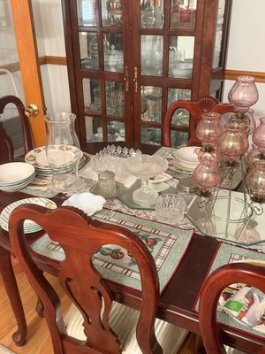 Sale Photo Thumbnail #13: Traditional wooden dining room set with carved chairs and matching china cabinet, featuring a collection of glassware and dishware.