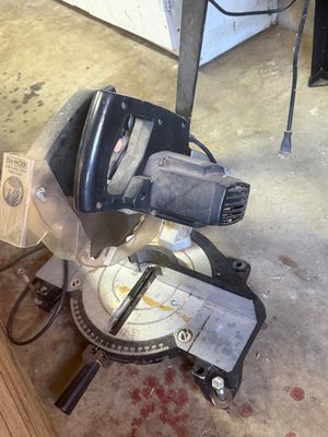 Sale Photo Thumbnail #12: Portable electric miter saw with clear blade guard, showing typical wear from workshop use.
