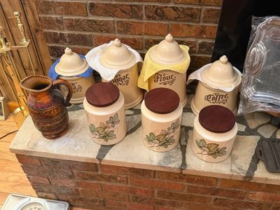 Sale Photo Thumbnail #23: Collection of vintage kitchen canisters, including a cream ceramic set with script labels and a trio with floral motifs and wooden lids.