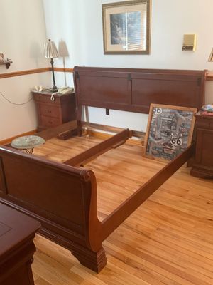 Sale Photo Thumbnail #15: Traditional cherry-finish sleigh bed frame, featuring a rolled headboard and footboard with matching wooden side rails.