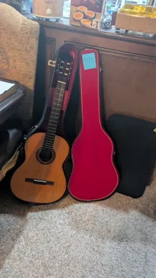 Acoustic classical guitar presented in a red plush-lined hard case, appearing in good pre-owned condition.