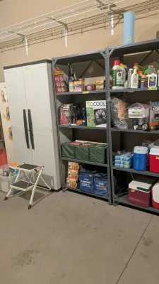 Garage organization items including metal shelving units, a plastic storage cabinet, small step stool, coolers, cleaning supplies, and...