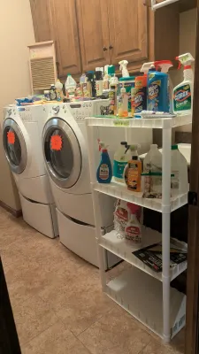 Laundry room items including front-loading washing machine and dryer set with pedestal drawers, a four-tier white plastic shelving unit,...