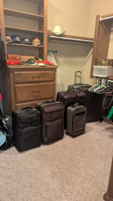 Assortment of modern rolling suitcases and soft-sided luggage arranged inside a walk-in closet.