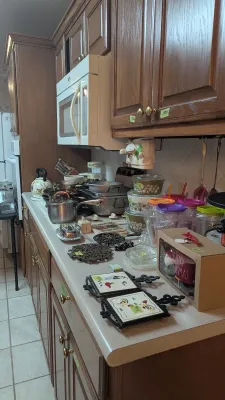 Sale Photo Thumbnail #3: Assorted vintage kitchenware and decor items arranged on a kitchen countertop, including CorningWare casserole dishes, stainless steel pots, trivets, and drinkware.