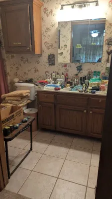 Sale Photo Thumbnail #18: Bathroom vanity filled with various toiletries and household items, accompanied by a oak medicine cabinet, wall cupboard, and a folding table.