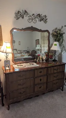 Sale Photo Thumbnail #21: French Provincial style triple dresser with a matching carved wood wall mirror, flanked by table lamps.