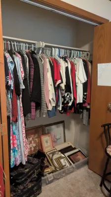 Sale Photo Thumbnail #7: Closet full of vintage women's clothing on hangers above framed wall art, decor items, and tapestry luggage.