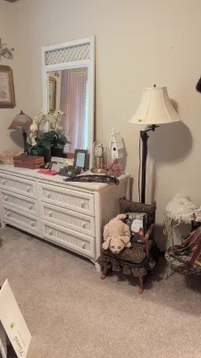 Sale Photo Thumbnail #12: White woven wicker dresser and matching wall mirror set paired with a tall dark metal floor lamp, child's rocking chair, and assorted decor.