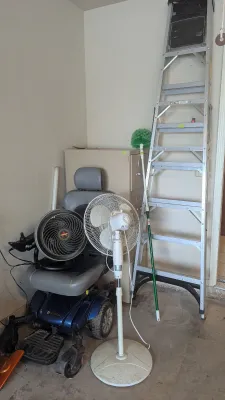 Sale Photo Thumbnail #33: Golden Technologies power wheelchair stored alongside a tall aluminum stepladder, floor fan, and file cabinet in a garage area.