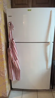 Sale Photo Thumbnail #37: White Whirlpool top-freezer refrigerator with a red-and-white striped apron hanging on the handle.