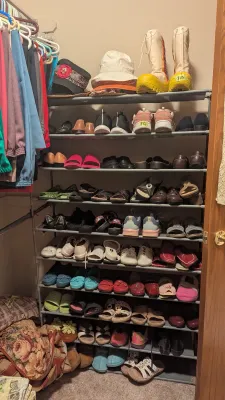 Sale Photo Thumbnail #16: Multi-tier freestanding shoe rack filled with various women's footwear, hats, and novelty boots inside a closet.