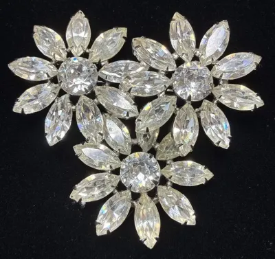 Sale Photo Thumbnail #79: Vintage silver-tone rhinestone brooch featuring a triple-flower spray design with round and marquise-cut clear stones.