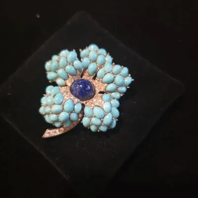 Sale Photo Thumbnail #22: Vintage flower brooch featuring cluster-set turquoise cabochons, a central dark blue lapis lazuli cabochon, and pavé rhinestone accents.