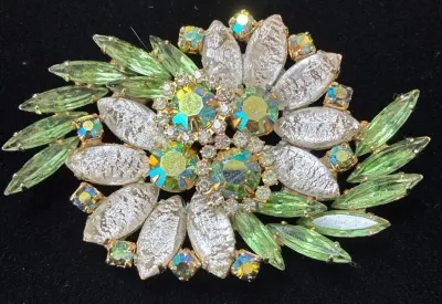 Sale Photo Thumbnail #95: Vintage floral burst rhinestone brooch featuring textured white glass stones, green marquise rhinestones, and aurora borealis accents.