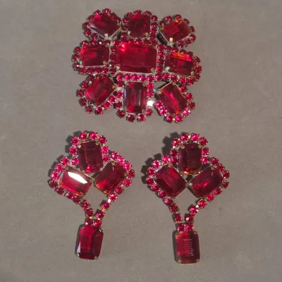 Sale Photo Thumbnail #28: Vintage ruby red rhinestone jewelry set featuring a large brooch and matching dangle clip-on earrings.