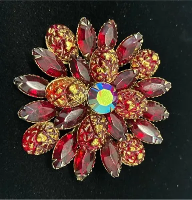 Sale Photo Thumbnail #58: Vintage flower-shaped costume jewelry brooch featuring red marquise rhinestones, gold-flecked cabochons, and an iridescent aurora borealis center stone.