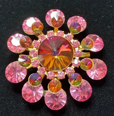 Sale Photo Thumbnail #107: Vintage starburst brooch featuring faceted pink rhinestones and iridescent aurora borealis accents set in gold-tone metal.