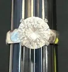 Sale Photo Thumbnail #20: Solitaire ring featuring a large, round brilliant-cut stone set in a simple four-prong silver-tone band.