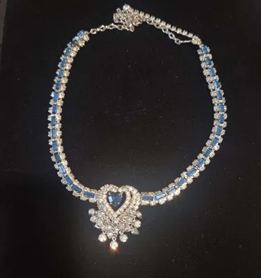 Sale Photo Thumbnail #32: Vintage rhinestone choker necklace featuring blue baguette stones and a central heart-shaped pendant with dangling accents.